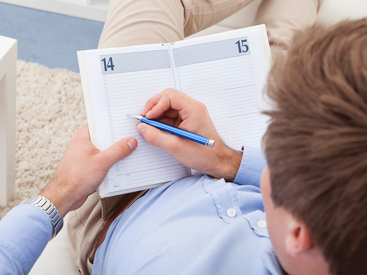 Overview shot of a male writing into a journal with a pencil