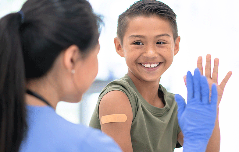 Medical worker and a cute boy high fiving after his vaccination